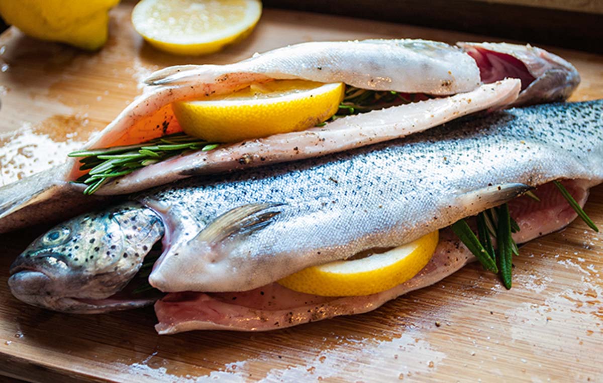 Die Forellen säubern, von beiden Seiten mit Salz und frisch gemahlenem Pfeffer würzen. In den Bauch Rosmarin und eine halbe Zitronenscheibe füllen. Foto: A. Jagiello