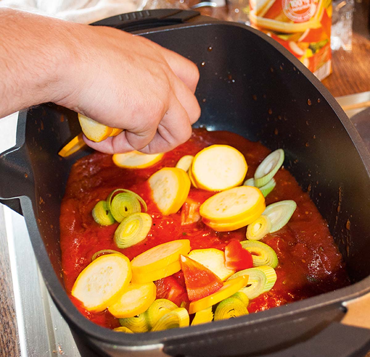 Das geschnittene Gemüse kommt nun zusammen mit der Tomatensoße in einen tiefen Bräter. Das Gemüse und die Soße müssen gut miteinander vermischt werden. Den Backofen auf 200 Grad vorheizen. Foto: A. Jagiello