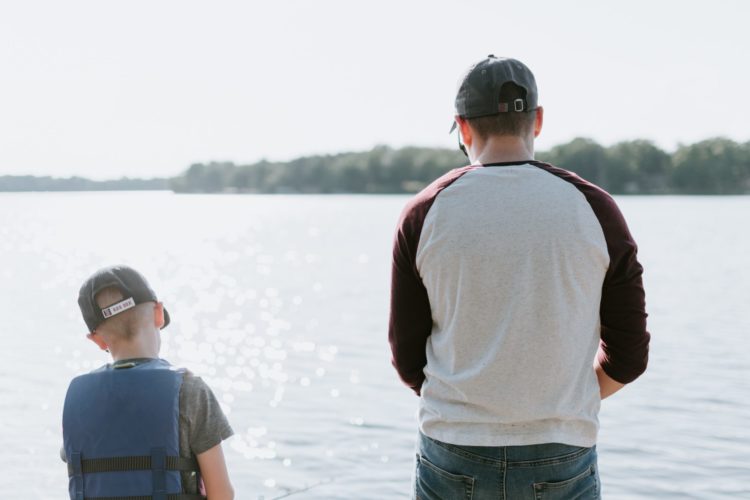 Vater und Sohn stehen nebeneinander und beobachten das Wasser.