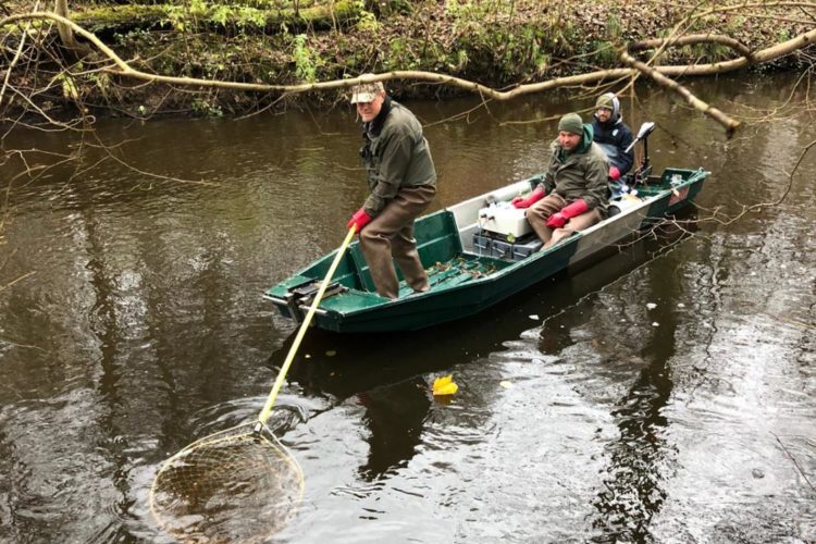 Angler auf einem Boot nutzen einen Kescher im Fluss.