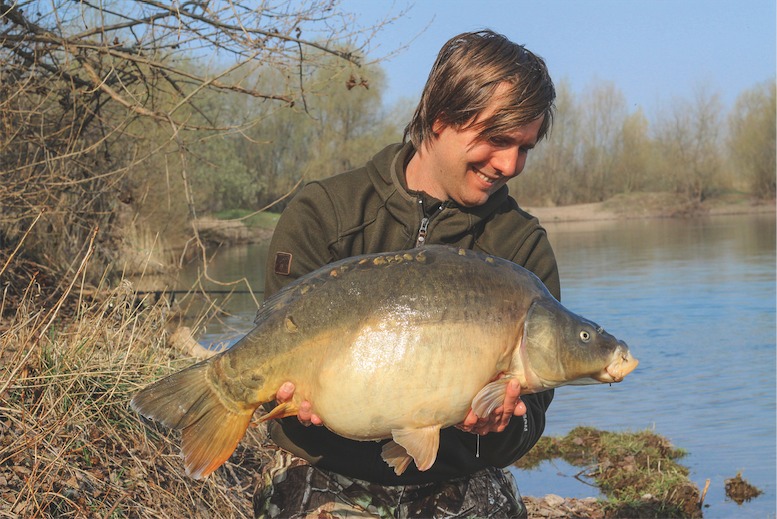 Angler mit Karpfen an einer Kiesgrube