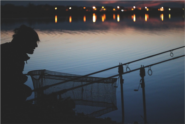 Silhouette von Angler am Ufer in der Nacht.