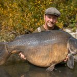 Angler mit kapitalen Karpfen im Arm.