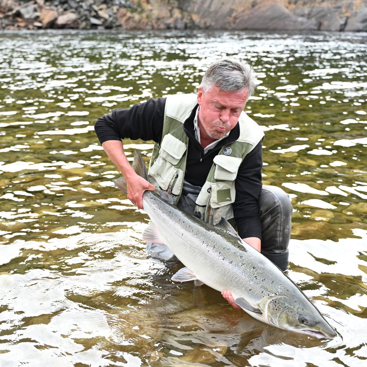 Angler mit Lachs in norwegischem Fluss
