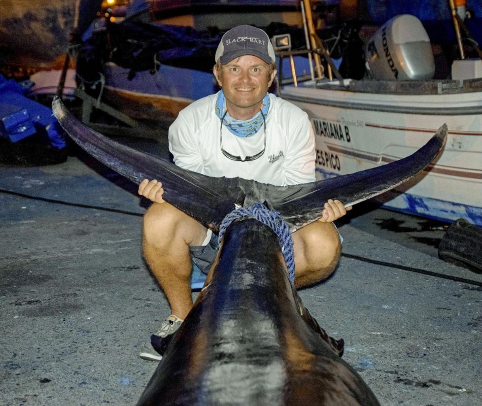 Angler mit der Schwanzflosse eines Marlins in den Händen