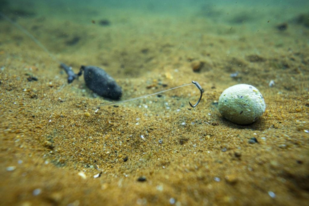 Eine Haarmontage aus monofiler Schnur, unter Wasser fotografiert. Die Präsentation ist nicht sauber, weil das steife Monofil den Haken quer vom Grund abstehen lässt.