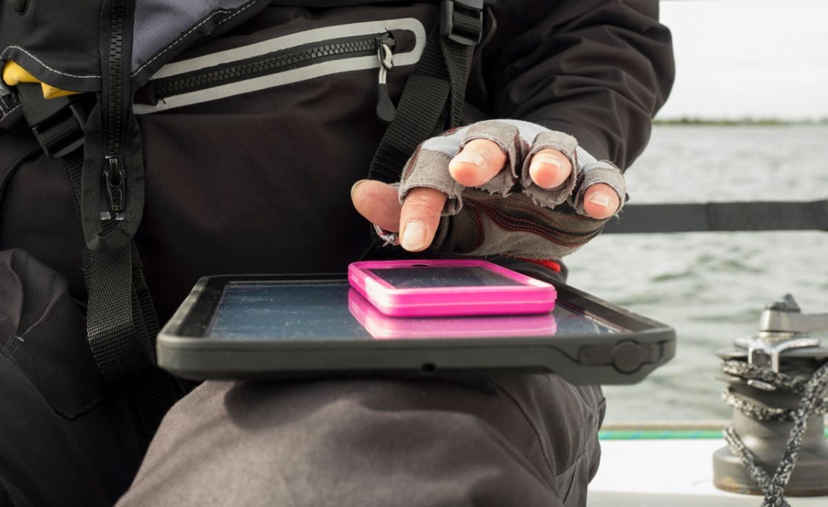 Angler mit Smartphone am Wasser