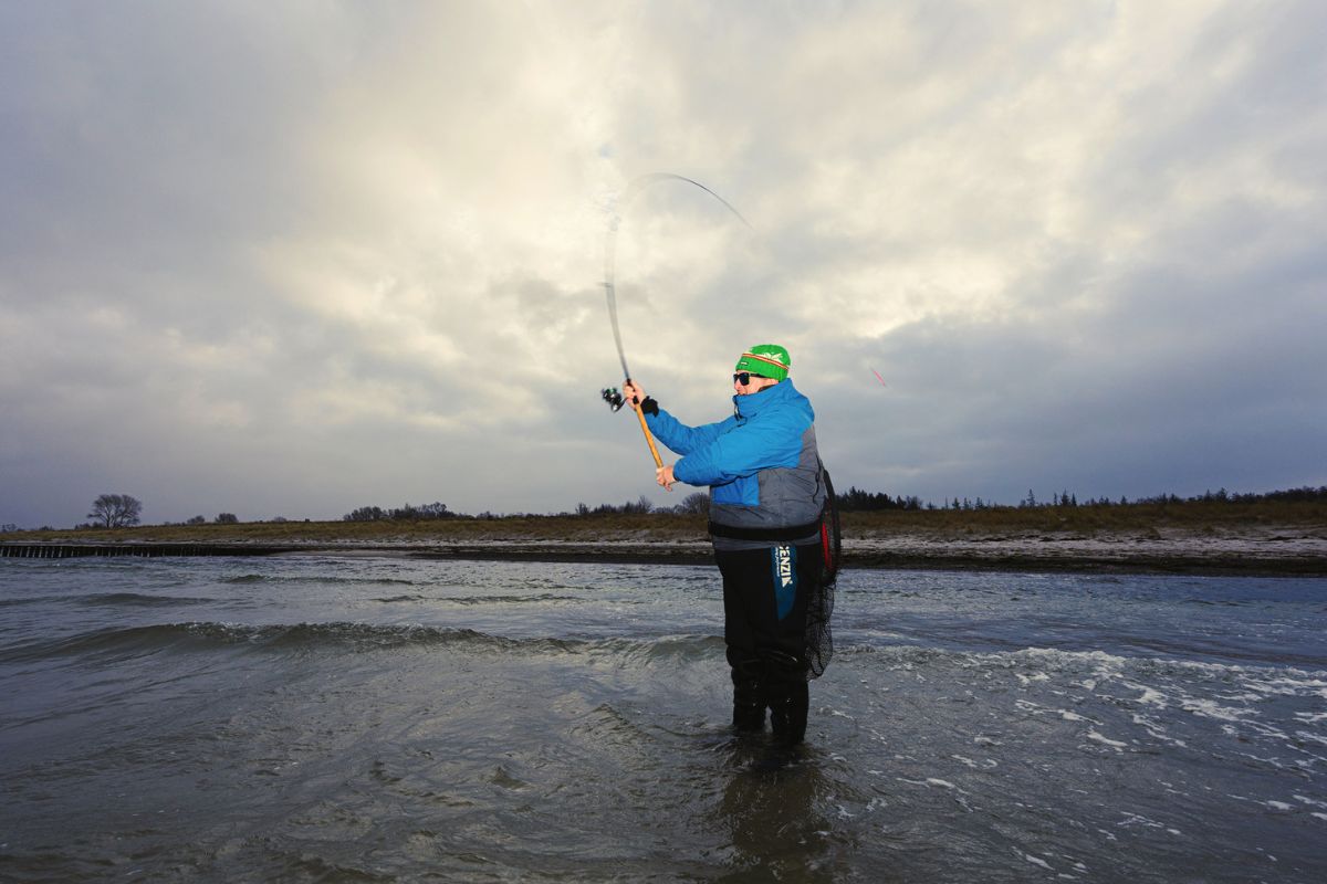 Angler fischt auf Meerforellen am Sandstrand