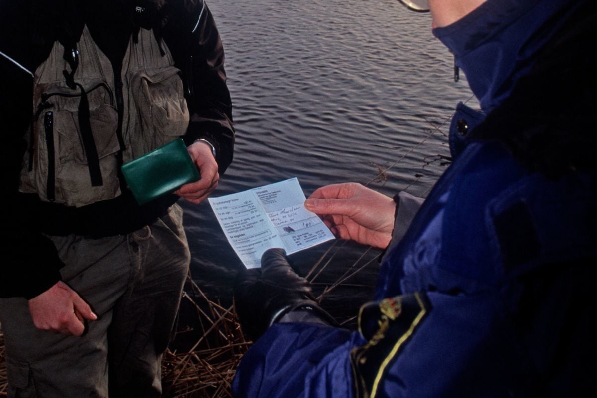 Ein Angler wird von der Fischereiaufsicht kontrolliert.