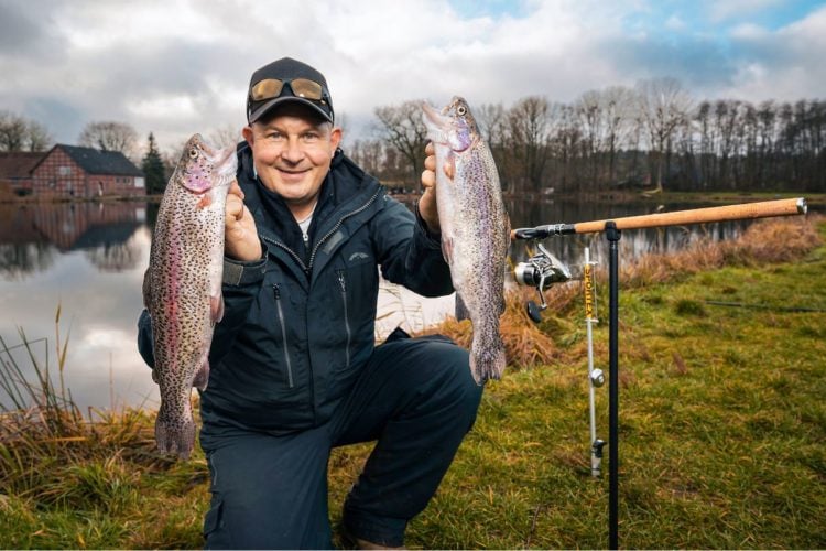 Angler mit zwei Forellen in der Hand angelt passiv am Forellensee